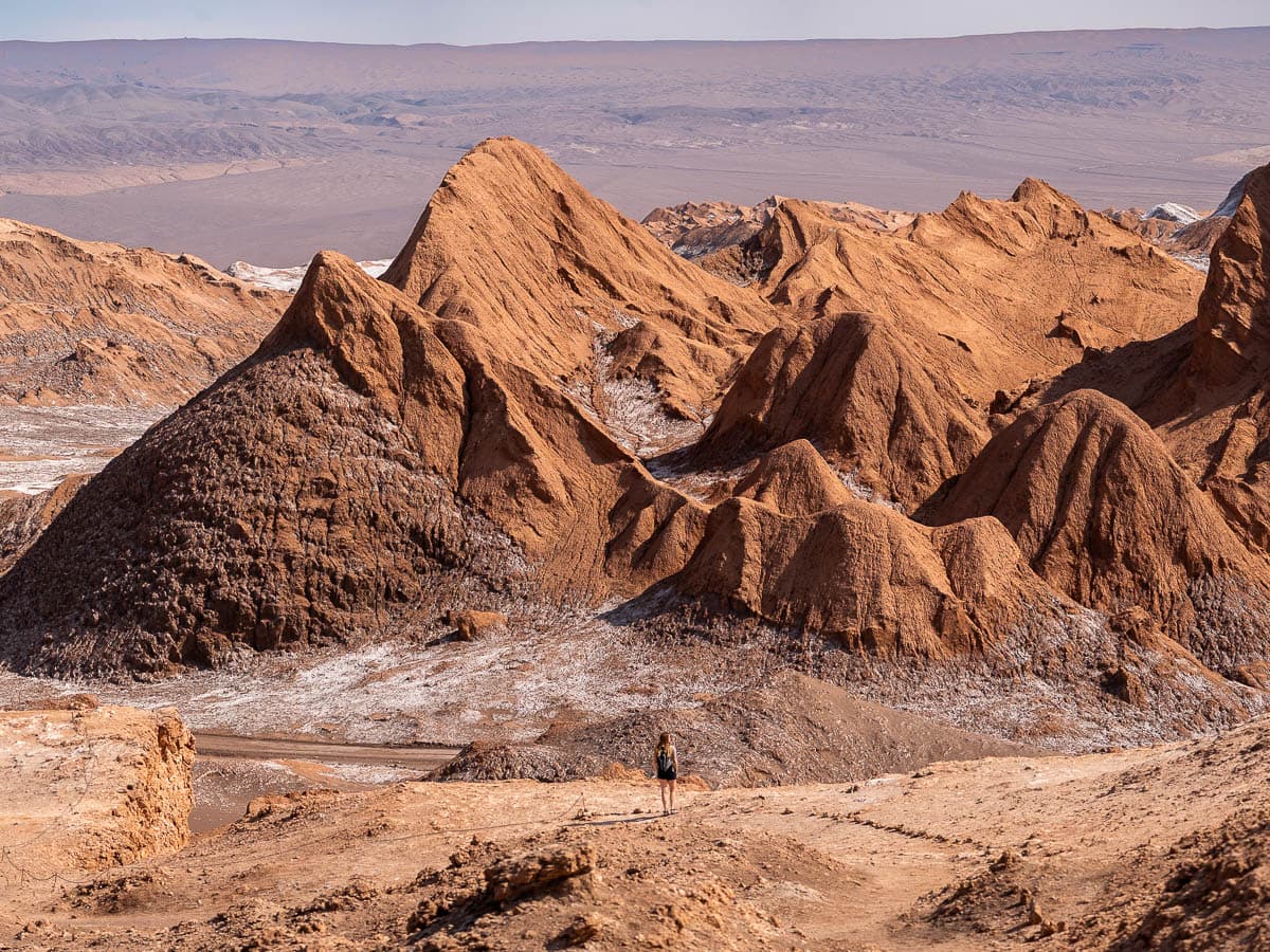 Woman standing on a ridge with jagged mountains in the background in Valle de la Luna in the Atacama Desert in Chile