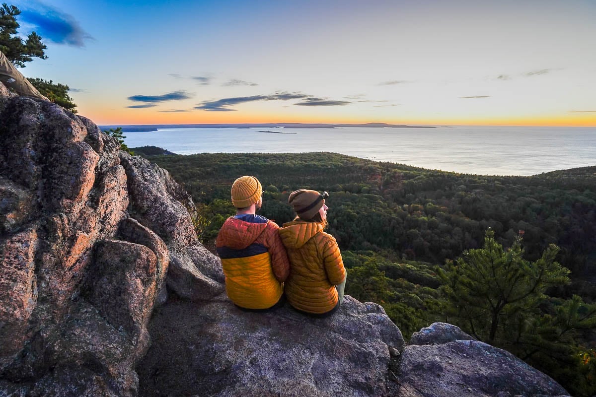 Couple sitting on the Beehive Trail at sunrise in Acadia National Park in Maine