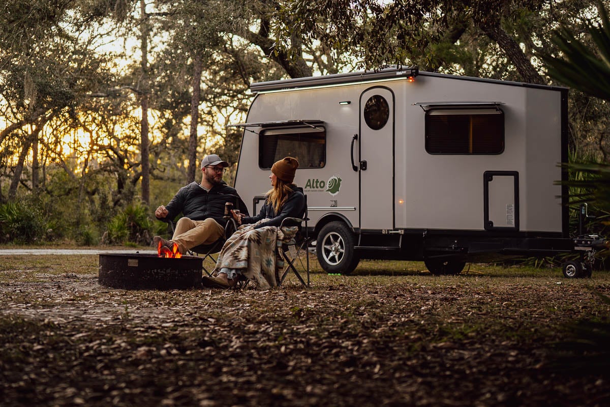 Couple sitting by a campfire in front of a Safari Condo Alto F1752 in Florida