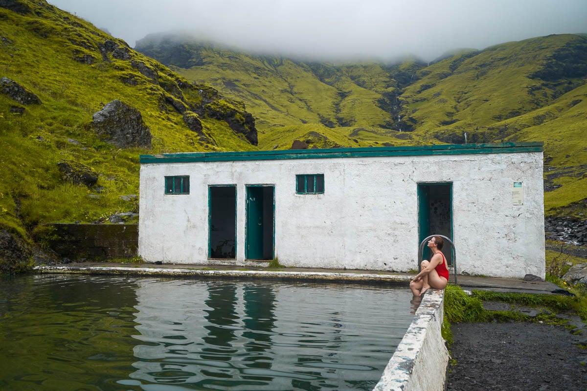 Woman sitting on the edge of the Seljavallalaug pool in Iceland