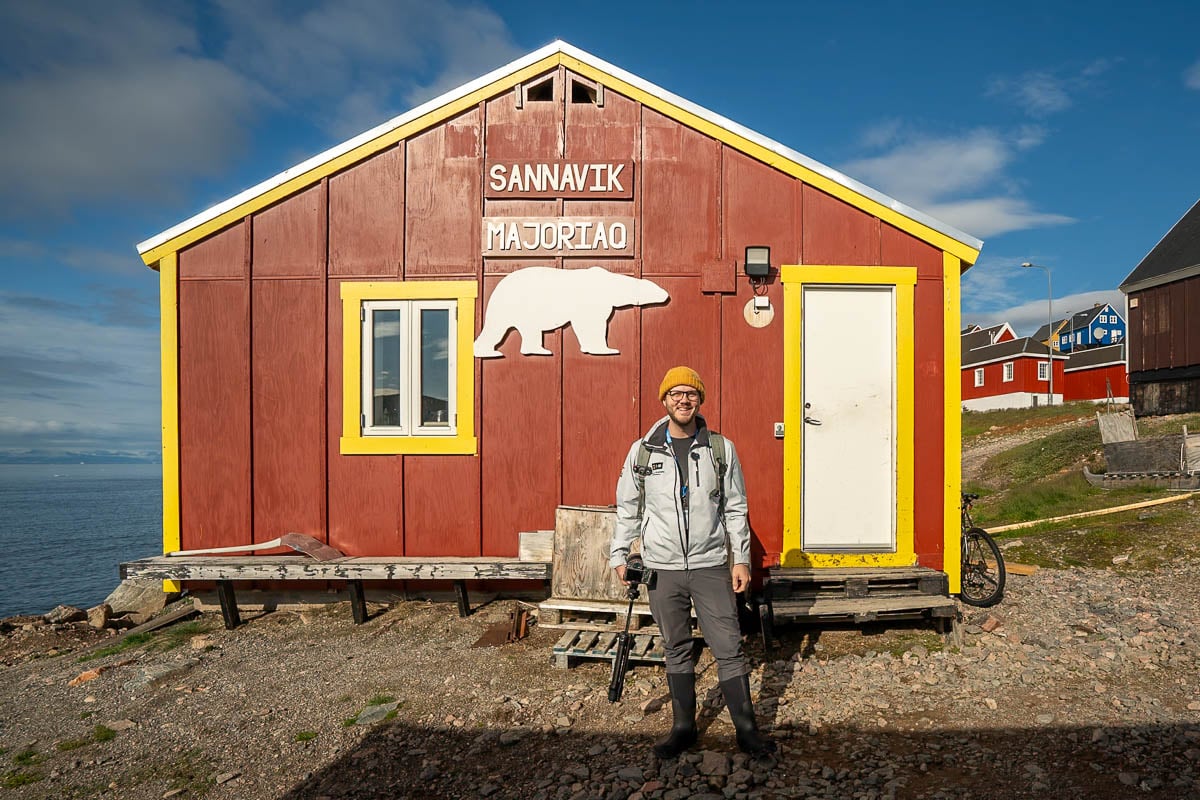 Man smiling in front of a red building in Ittoqqortoormiit, Greenland