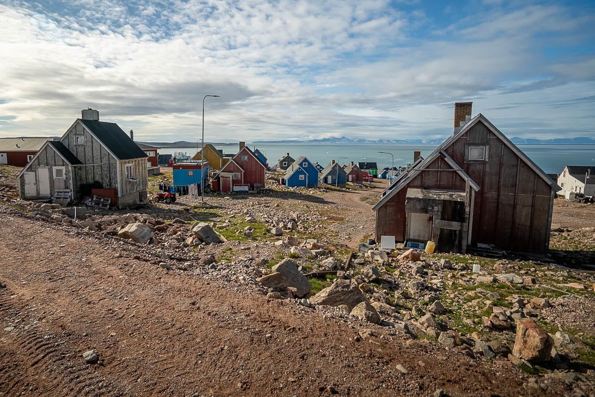 Colorful buildings on a rocky hillside with the Scoresby Sund in the background in Ittoqqortoormiit, Greenland