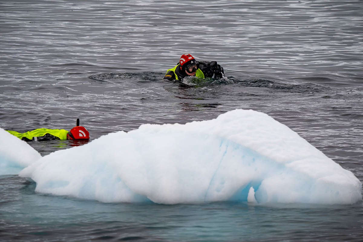 People snorkeling with icebergs in Antarctica