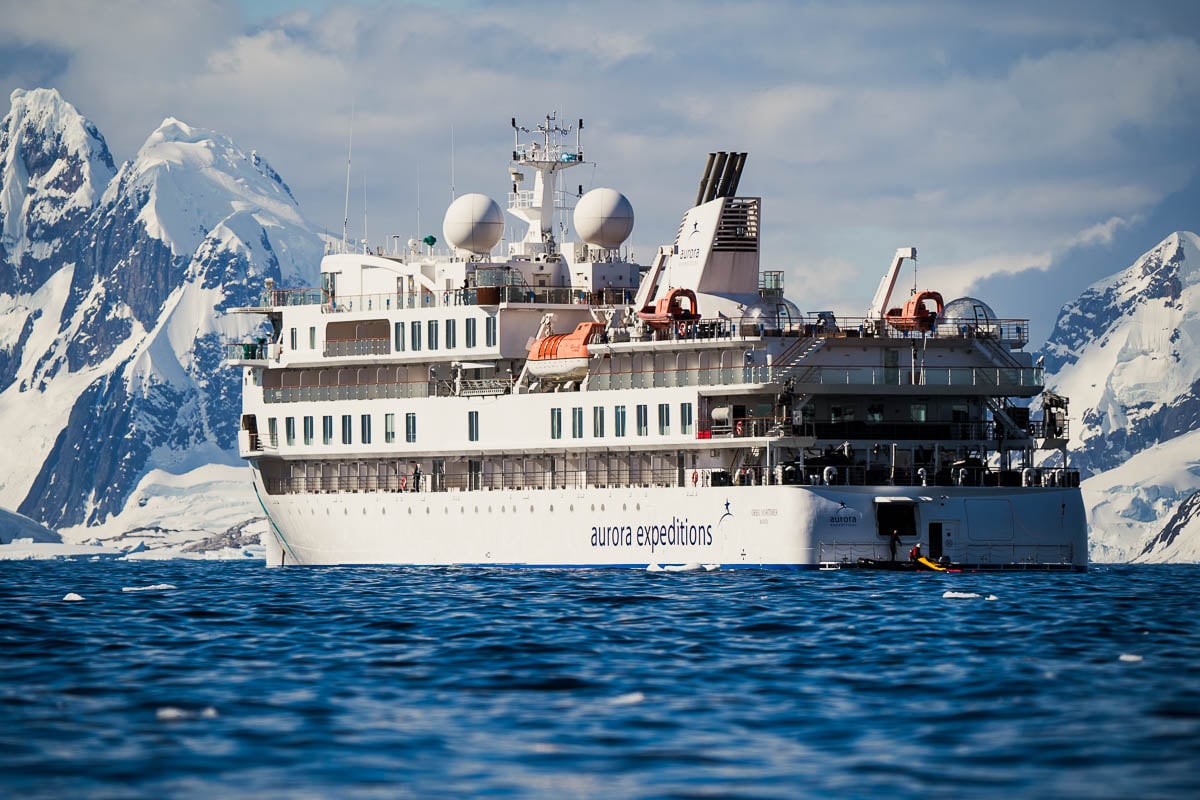 Greg Mortimer ship with snowy mountains in the background in Antarctica