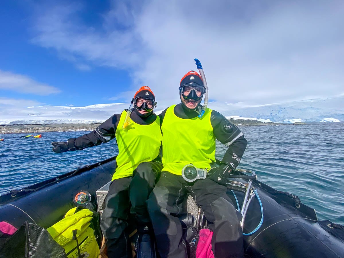 Couple wearing drysuits and snorkeling gear on an Aurora Expeditions Antarctica cruise with Sprightly Island in the background