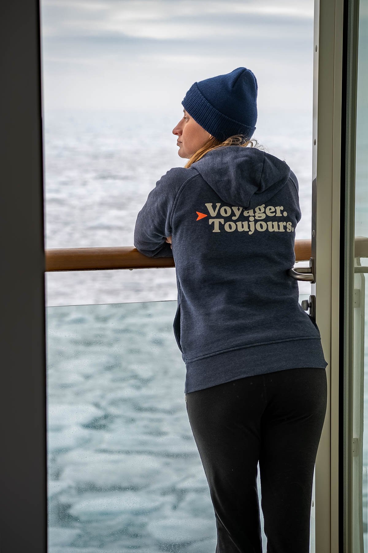 Woman standing at the balcony with pack ice in the background on Aurora Expeditions Sylvia Earle ship in Svalbard, Norway
