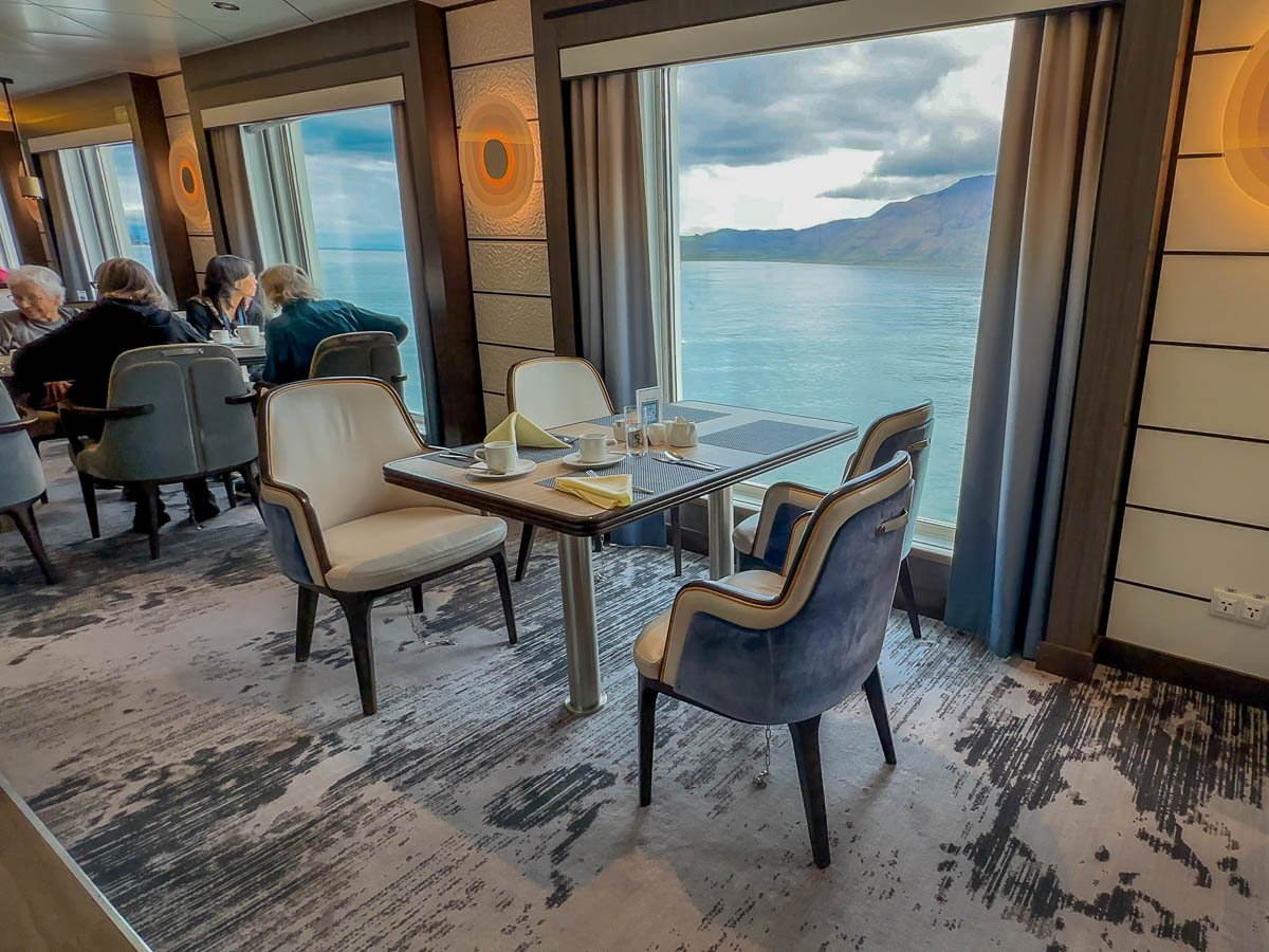 Table with four chairs in the Gentoo Dining Room on Aurora Expeditions Sylvia Earle ship with Longyearbyen in the background in Svalbard, Norway
