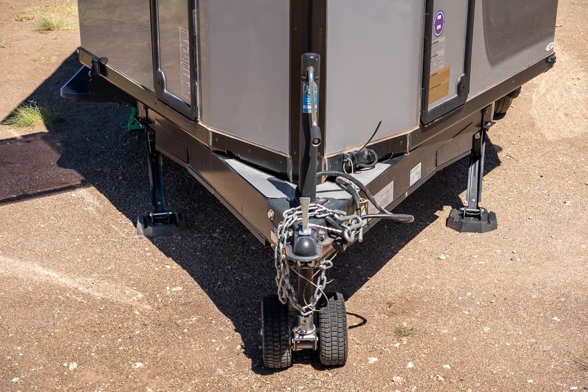 Front part of the Safari Condo Alto A1752 with a dolly and stabilizing jacks with RV jack pads resting on a sandy surface