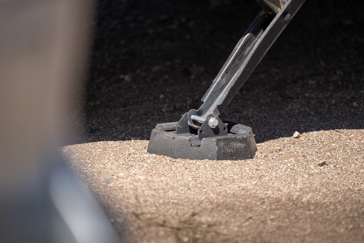 Stabilizer with an RV jack pad attached to it resting on a sandy surface