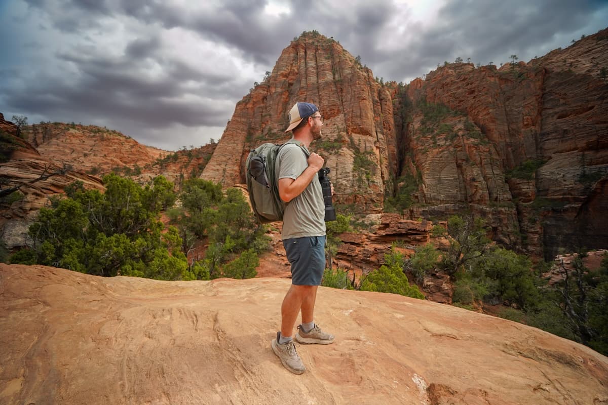 Man standing along the Canyon Overlook Trail with a sandstone mountain in the background in Zion National Park