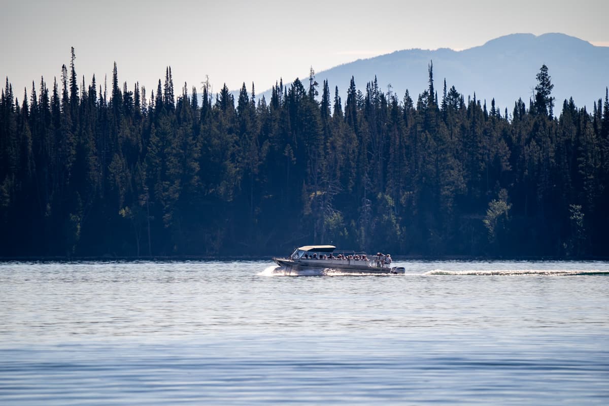 Boat shuttle crossing Jenny Lake with pine trees in the background from the Jenny Lake Trail in Grand Teton National Park in Wyoming