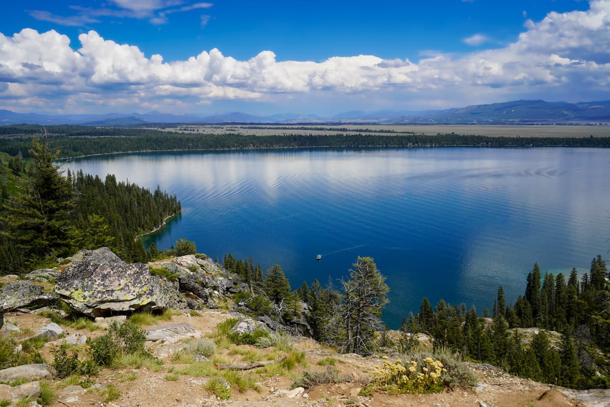 View of boat crossing Jenny Lake with mountains in the background in Inspiration Point along the Cascade Canyon Trail in Grand Teton National Park in Wyoming