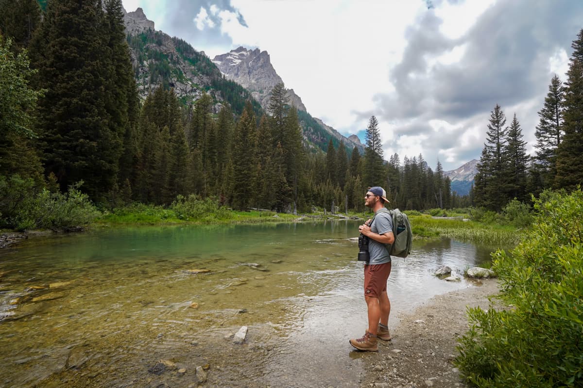 Man standing on the banks of Cascade Creek with the Teton Mountains in the background along the Cascade Creek Trail in Grand Teton National Park in Wyoming