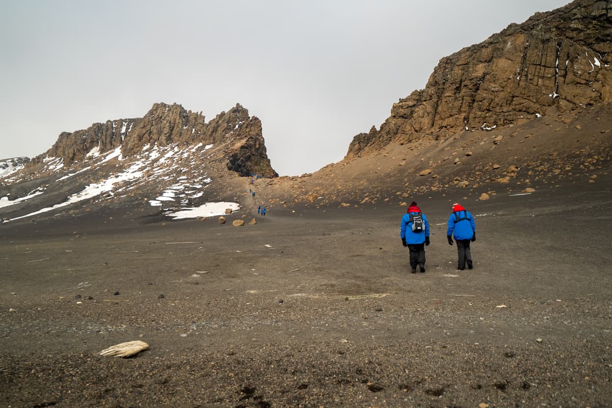 Antarctica cruise ship passengers hiking up a rocky hill on Deception Island, Antarctica