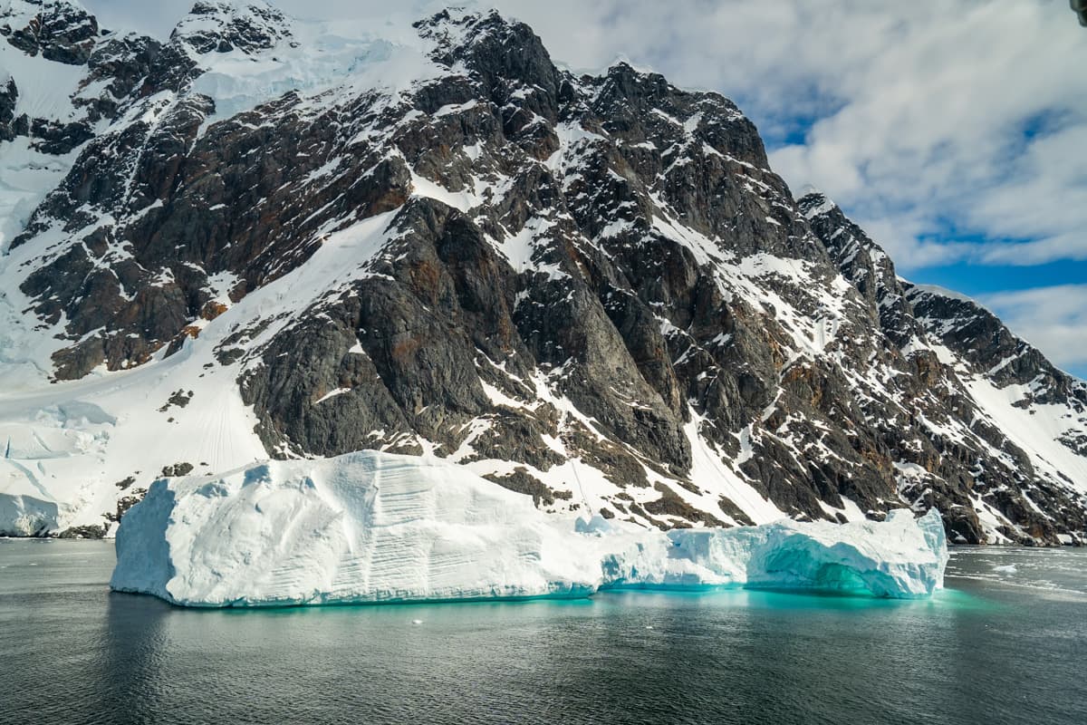 Flating iceberg with snow-covered mountain in the background in the Lemaire Channel of Antarctica