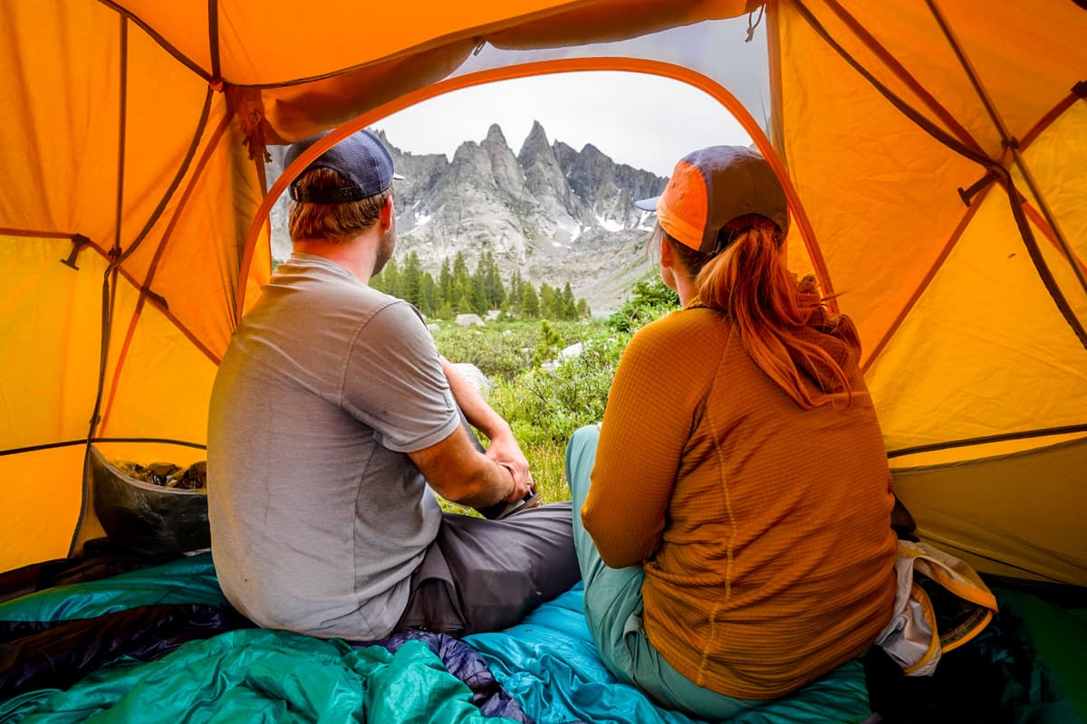 Couple sitting in their tent looking at the backside of the Cirque of the Towers in the Wind River range in Wyoming
