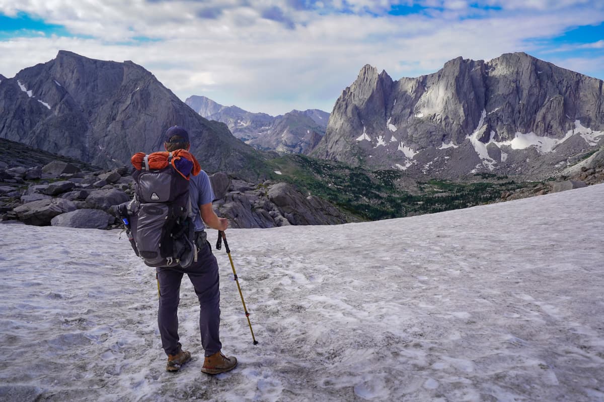 Man standing on a snow patch looking at the Cirque of the Towers from Texas Pass in the Wind River Range of Wyoming