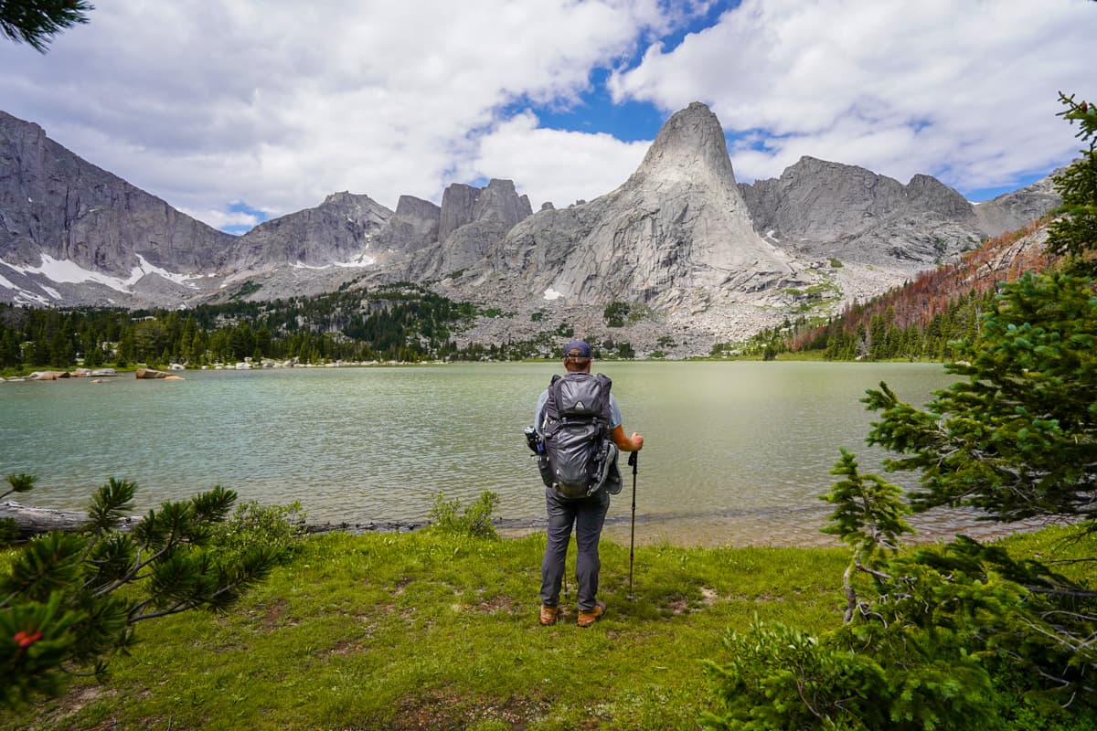 Man standing at the shoreline of Lonesome Lake with Cirque of the Towers in the background in the Wind River range in Wyoming