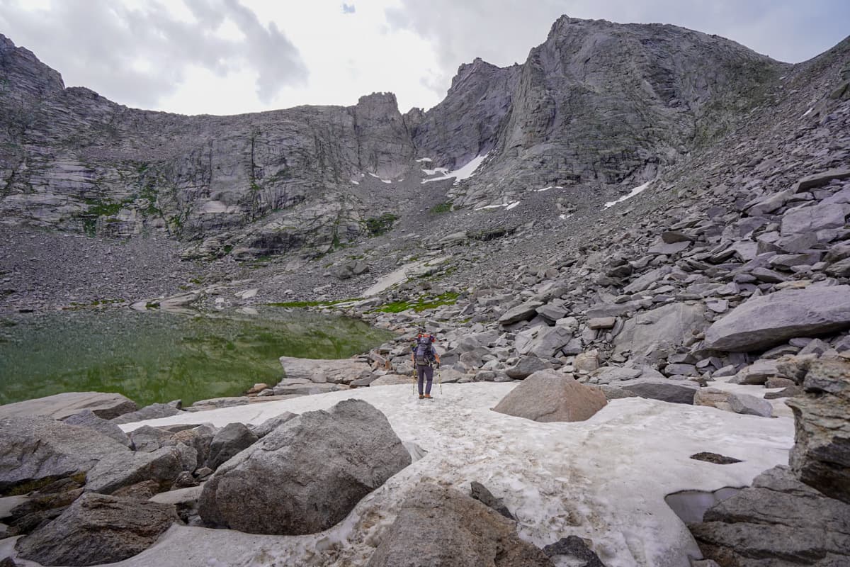 Man walking across a snow patch by Texas Pass along the Cirque of the Towers Trail in the Wind River range in Wyoming