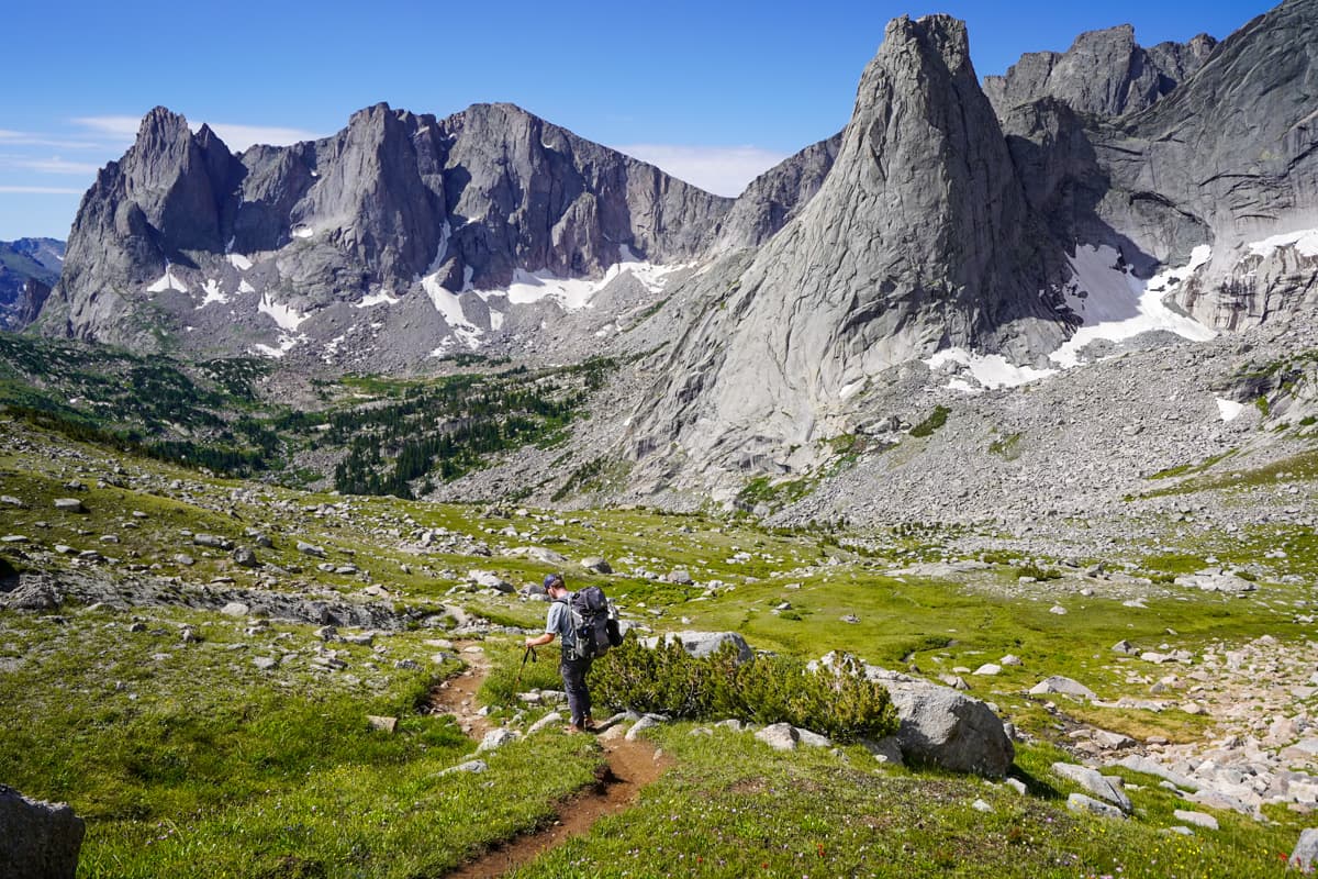 Man climbing down Texas Pass with the Cirque of the Towers mountains in the background in the Wind River range in Wyoming