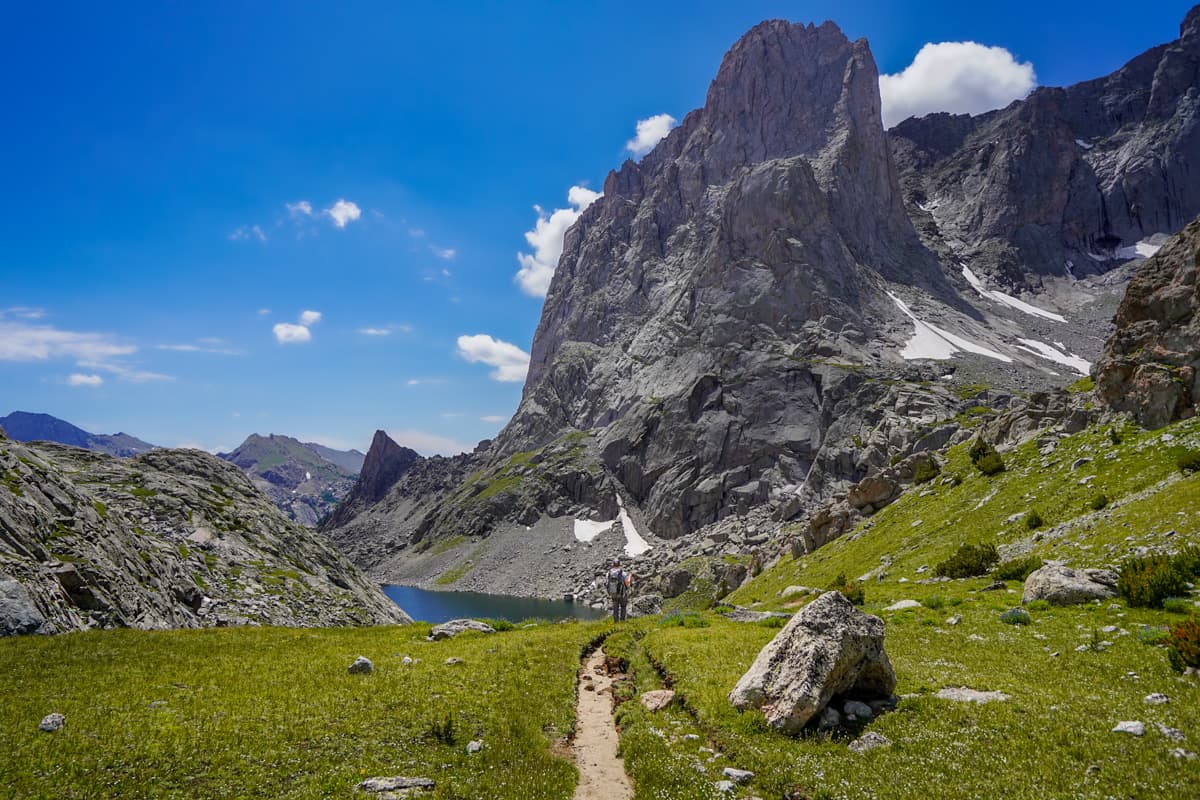 Man walking along the Cirque of the Towers trail with a granite monolith in the background along the Cirque of the Towers trail in Wyoming