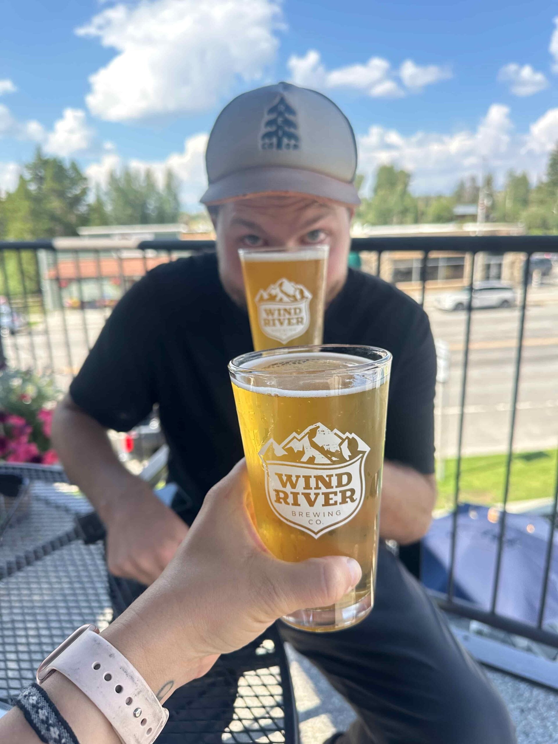 Woman holding a Wind River Brewing Co glass in front of a man holding another glass in Pinedale, wyoming