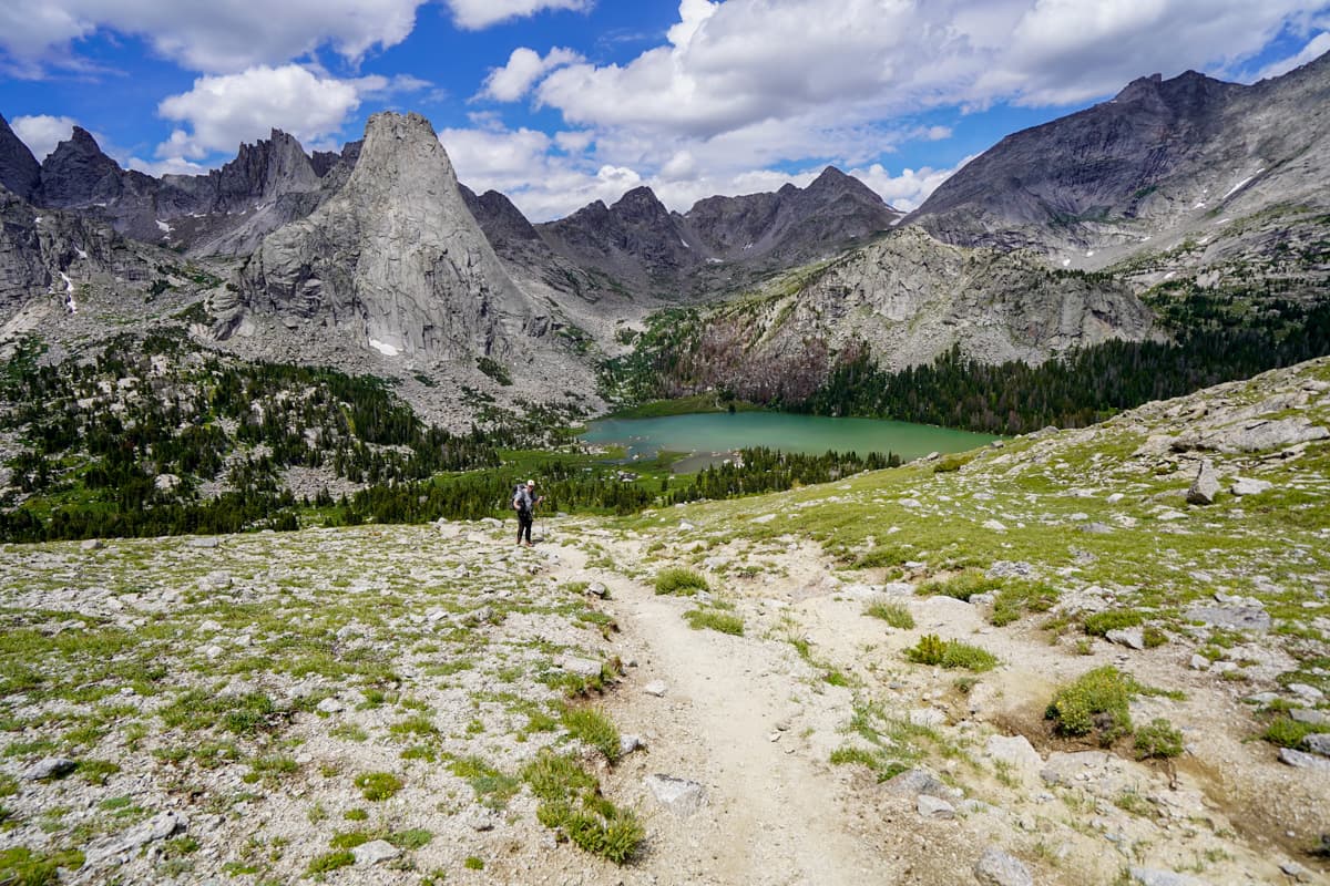 Man climbing up to JackassPass with Cirque of the Towers and Lonesome Lake in the background in the Wind River range in Wyoming