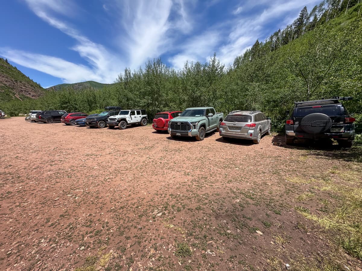 Cars parked in a gravel parking lot at the Conundrum Hot Springs trailhead in Maroon Bells-Snowmass Wilderness in Aspen, Colorado