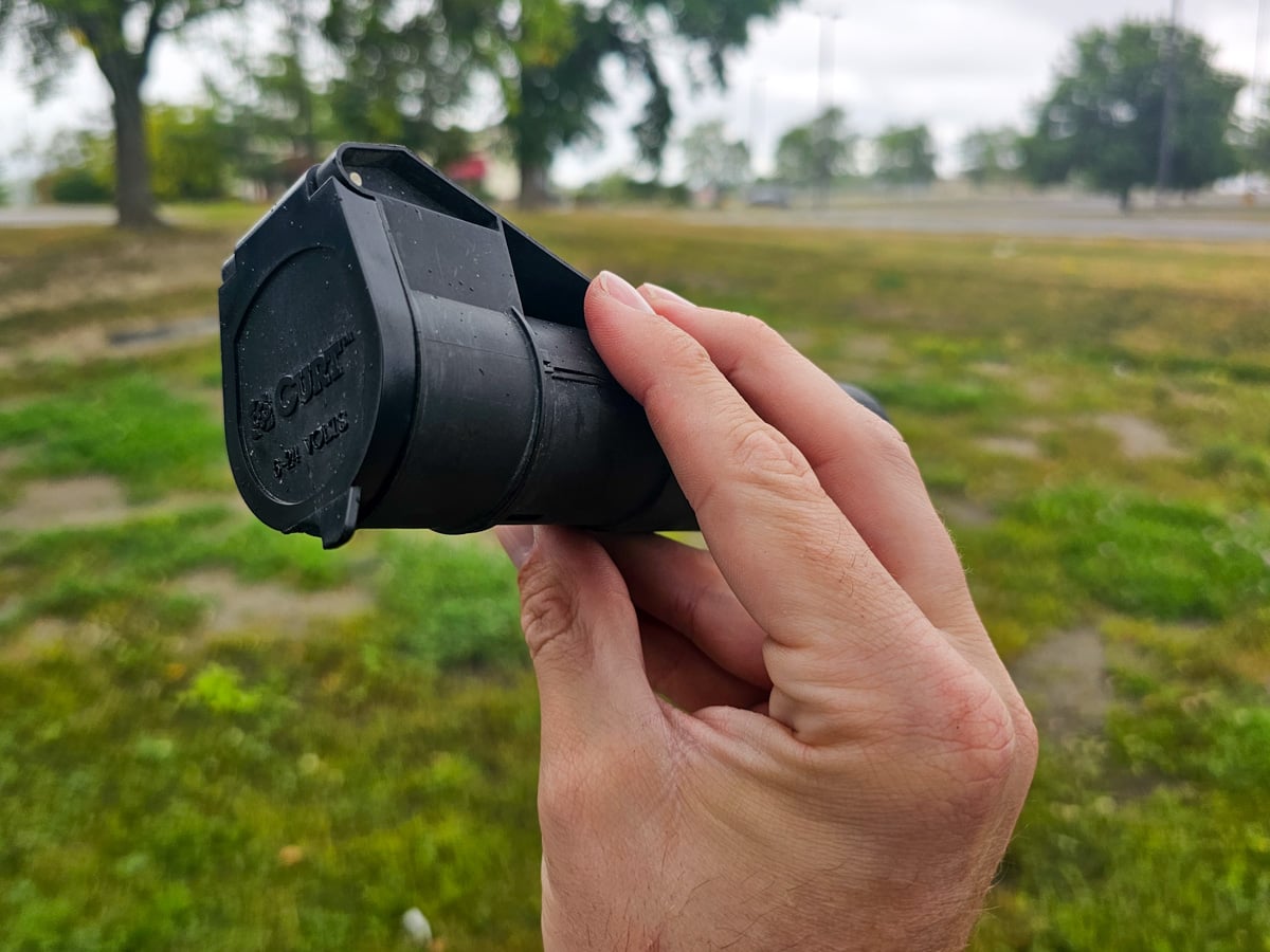 Man holding a Curt Echo wireless brake controller with a grassy field in the background