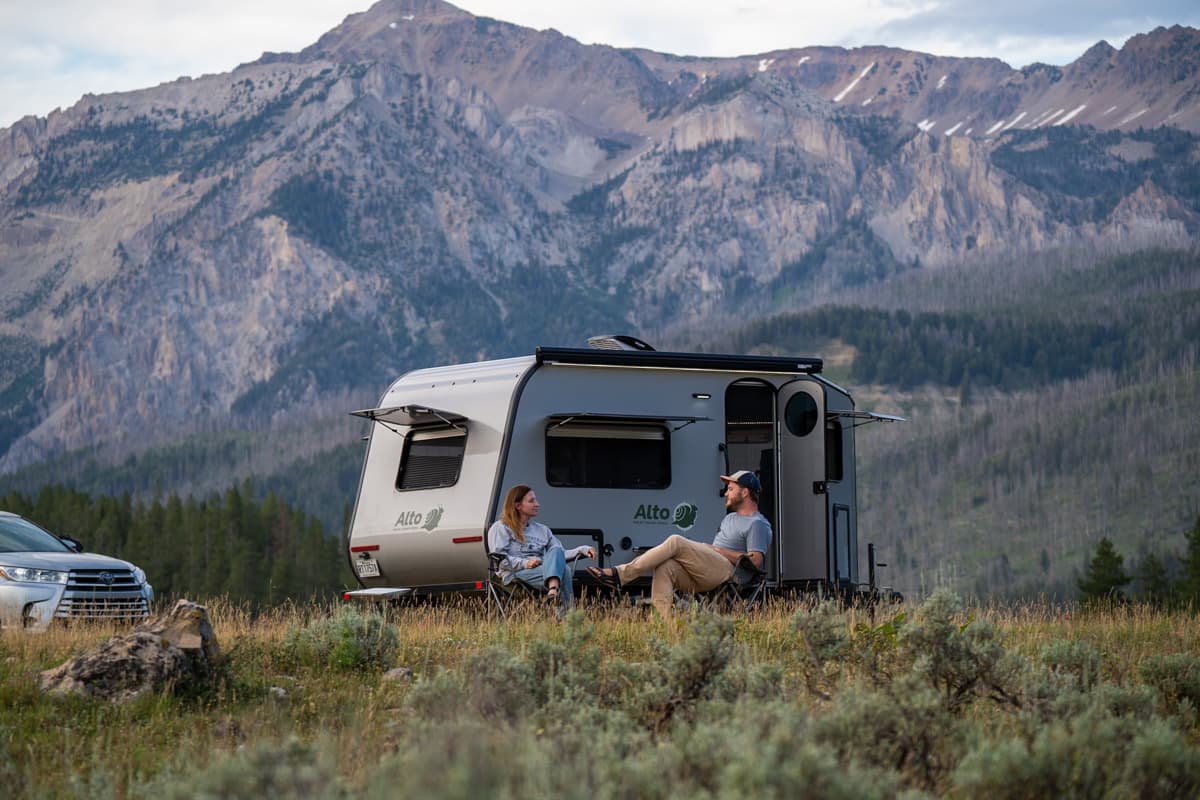 Couple sitting in front of a Safari Condo Alto A1752 in front of a mountain in Jackson, Wyoming