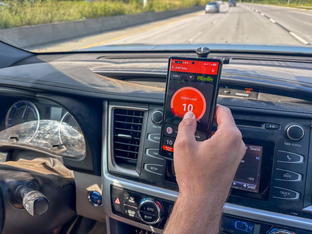 Man pressing the manual override button on the OneControl Auto app for the Curt Echo Wireless Brake Controller