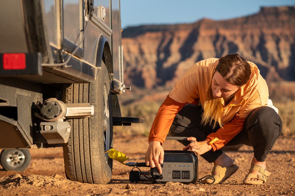 Woman filling up a trailer tire with a sandstone mountain in the background outside of Zion National Park, Utah