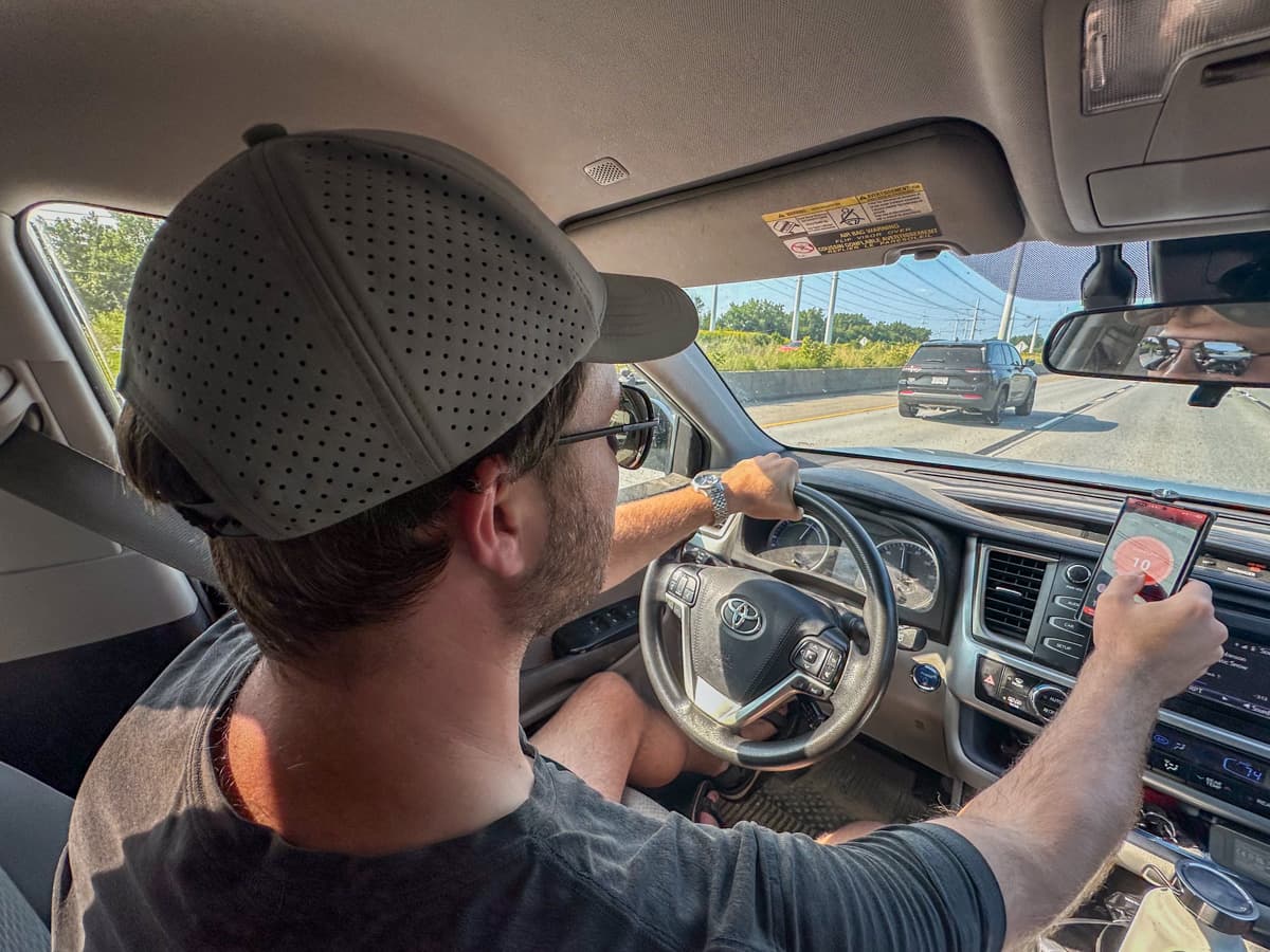 Man driving and pressing the manual override button on the OneControl Auto app for the Curt Echo wireless brake controller on his phone