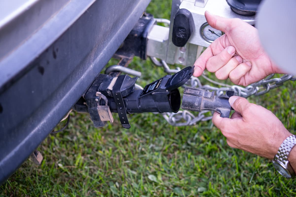Man plugging in a trailer's seven pin connector to the Curt Echo Wireless Brake controller on the rear of a vehicle