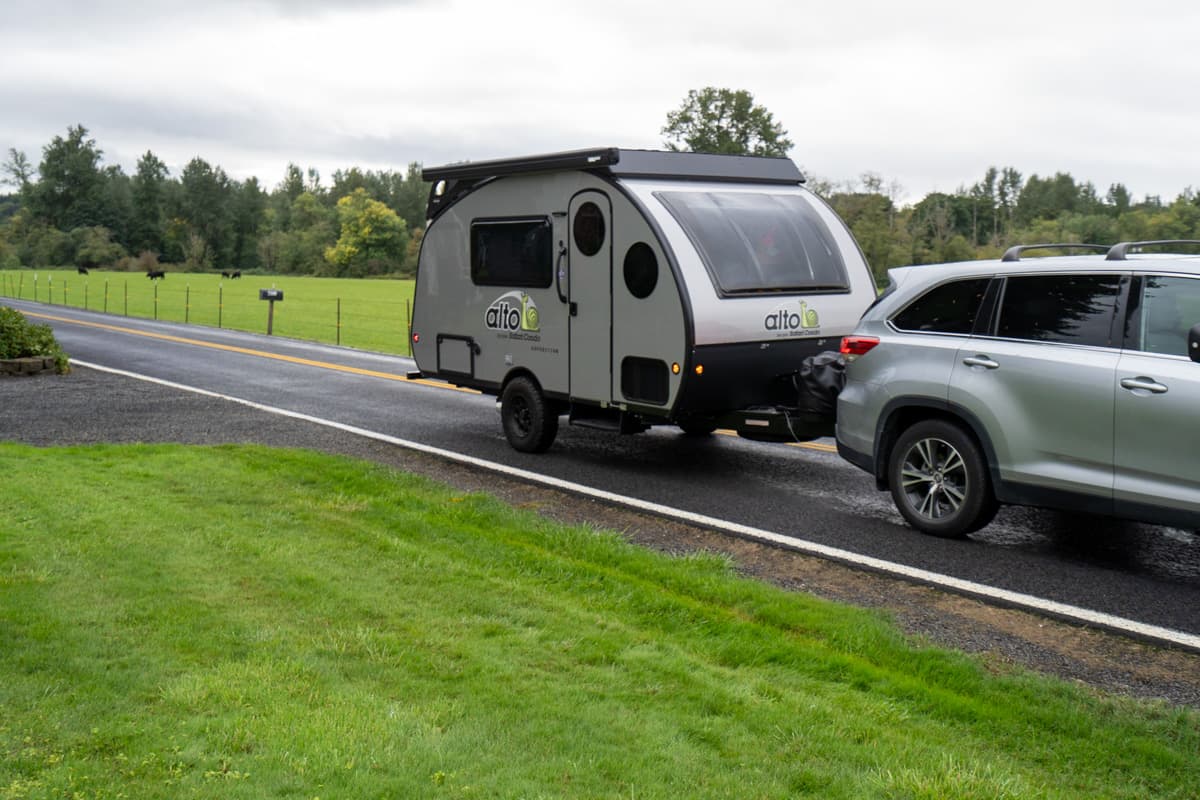 SUV pulling a Safari Condo Alto Expedition F1743 on a road in a rural setting