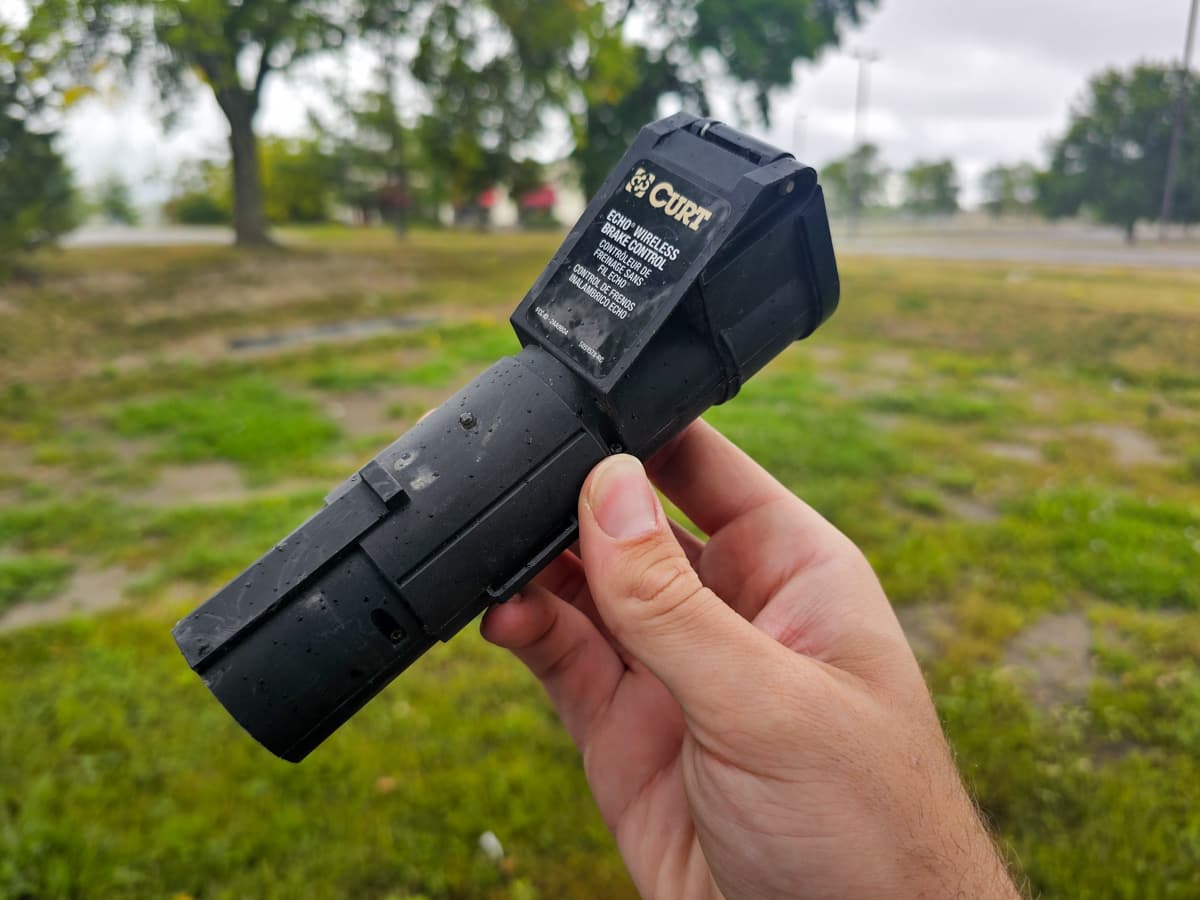Man holding a Curt Echo Wireless Brake Controller in his hand with a grassy background