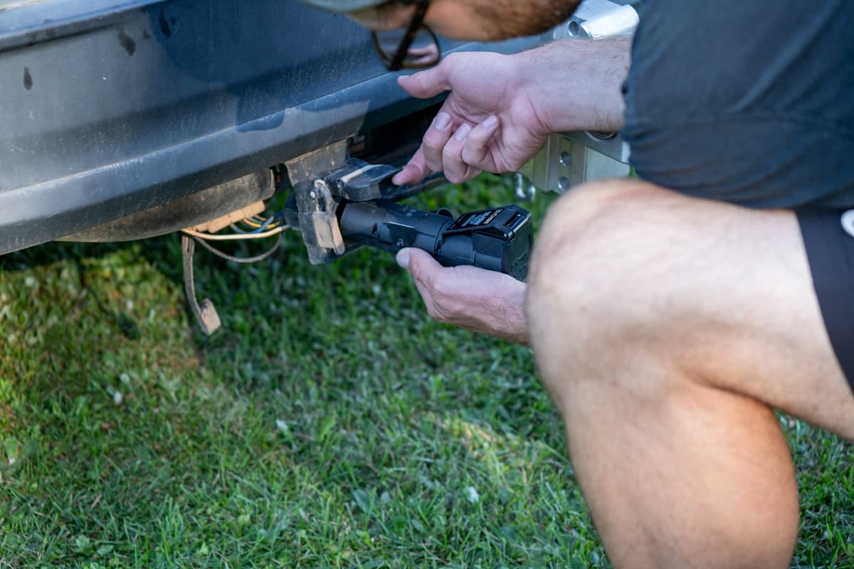Man plugging in a Curt Echo Wireless brake controller into the seven pin connector on his SUV
