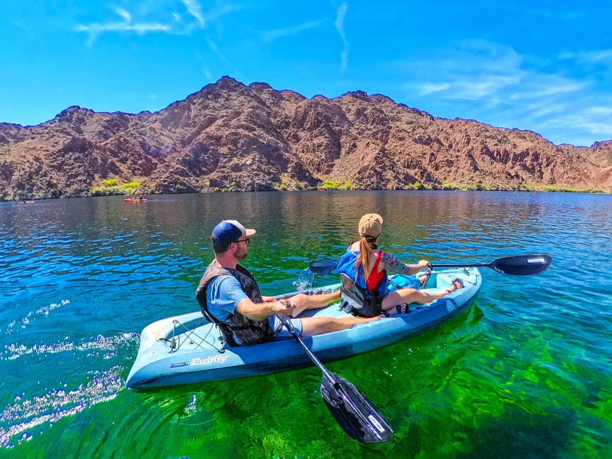 Couple kayaking down the Colorado River with a red rock canyon in the background in Lake Mead National Recreation Area in Willow, Arizona