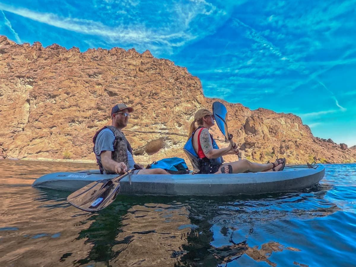Couple kayaking down the Colorado River with red rock canyon in the background in Lake Mead National Recreation Area in Willow, Arizona