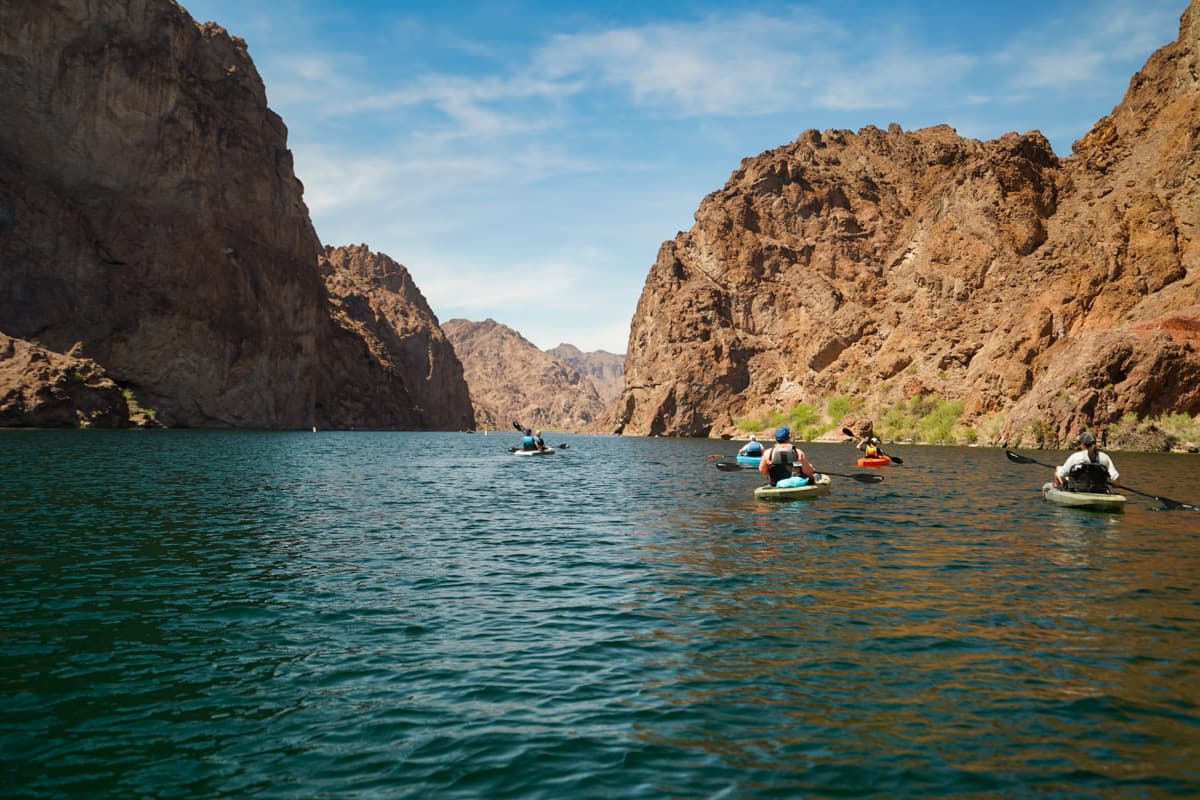 People kayaking down the Colorado River with surrounding canyon formations in the Lake Mead National Recreation Area in Willow, Arizona