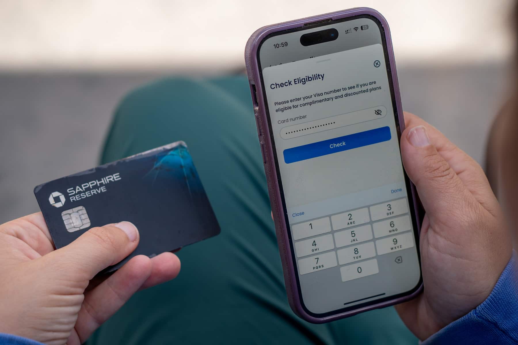 Woman holding up her credit card next to her cell phone to check eligibility for a free GigSky eSiM