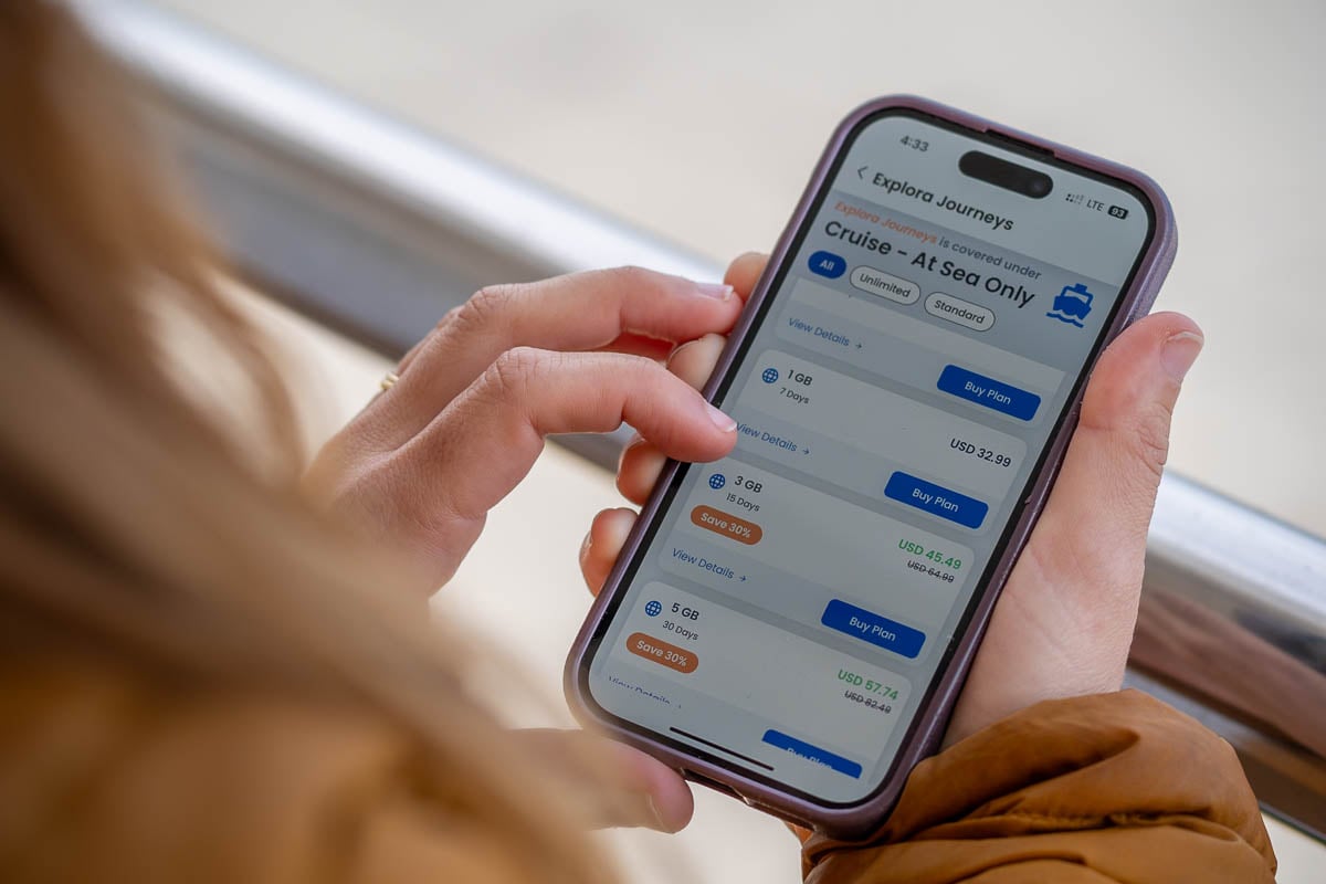 Woman looking at a cell phone with different GigSky eSIM plans for cruise eSIM options