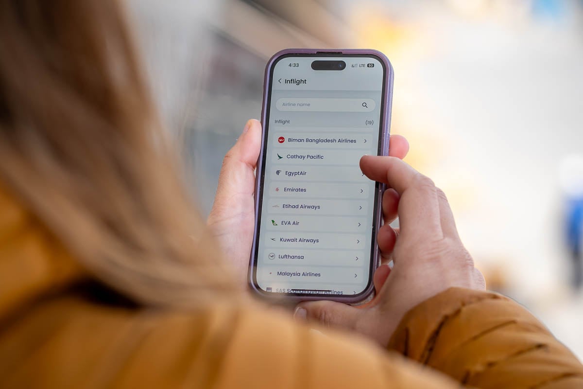 Woman looking at a cell phone with different GigSky eSIM plans for a variety of airlines
