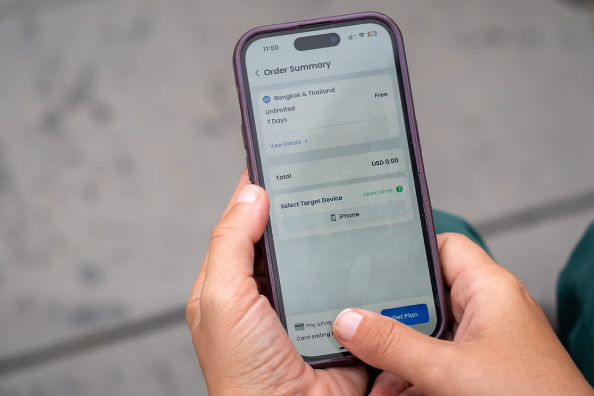Woman holding a cell phone with a free GigSky eSIM plan for Thailand