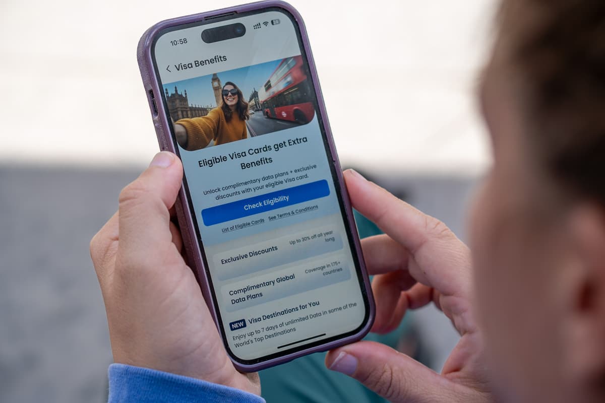 Woman looking at a cell phone with Visa perks for a free GigSky eSIM