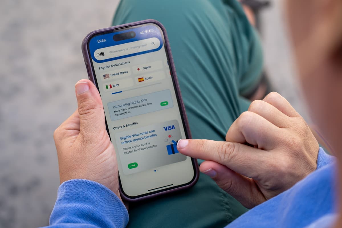 Woman looking at a cell phone with a Visa perk for a free GigSky eSIM