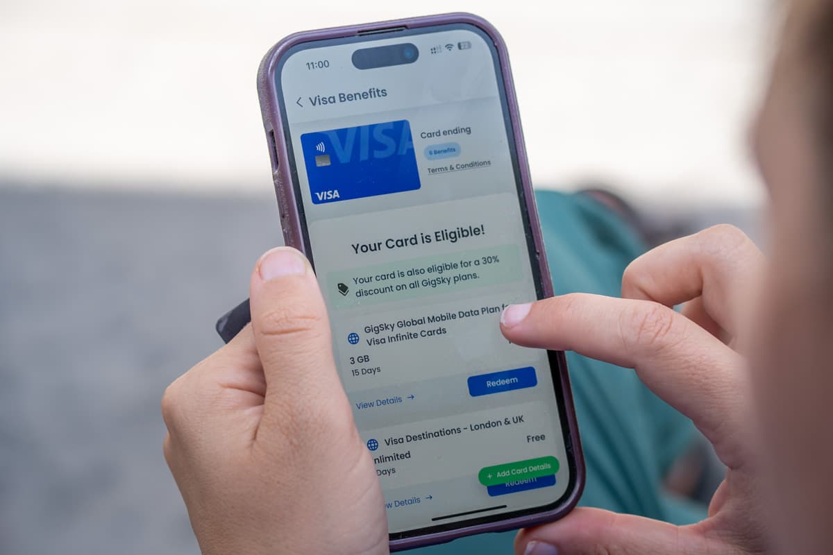 Woman holding cell phone looking at free eSIM from GigSky as a Visa perk