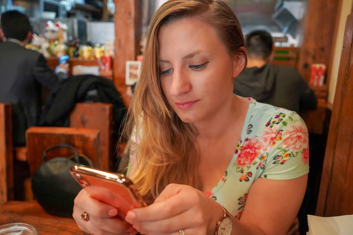 Woman looking at her cell phone while sitting at a table in a restaurant