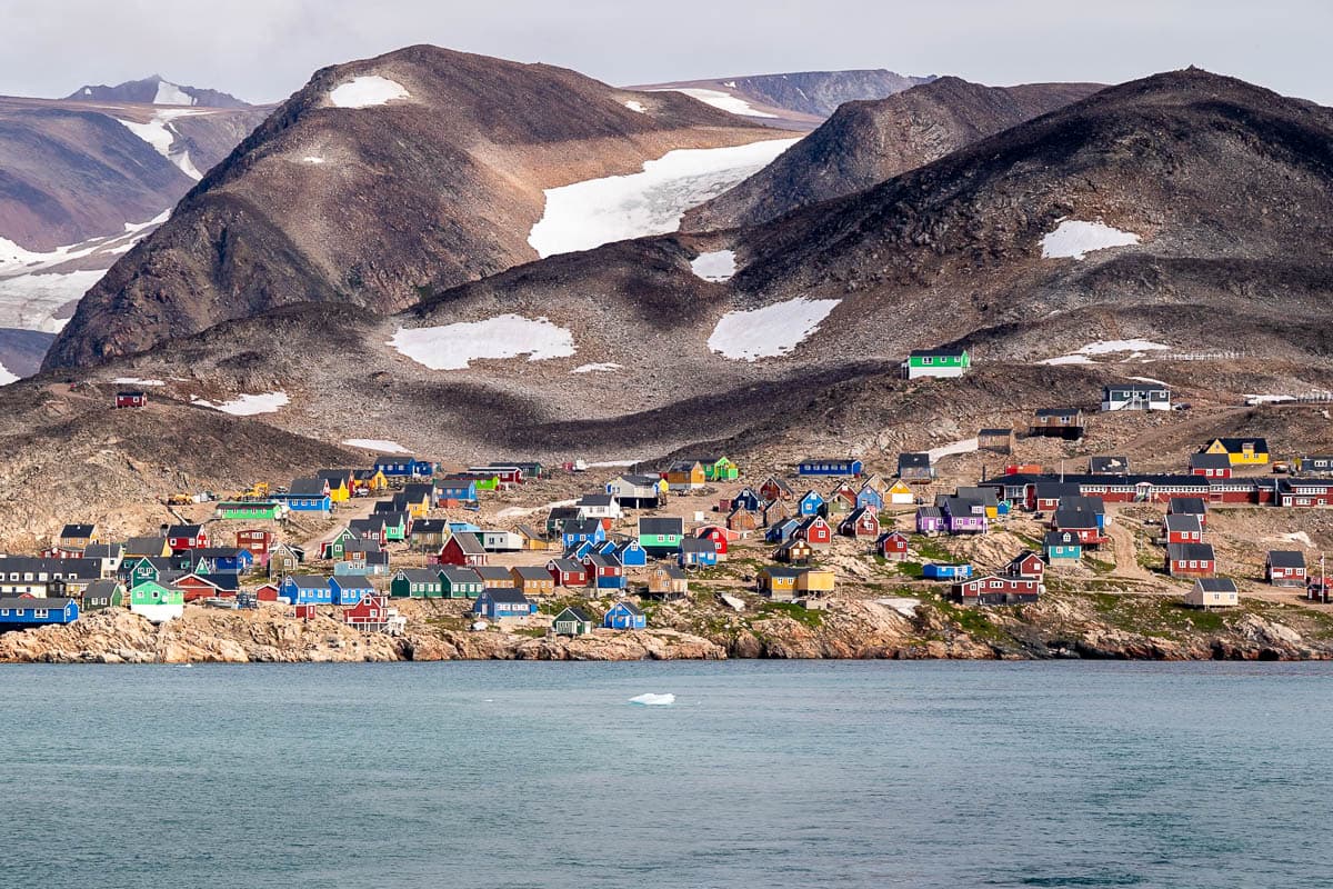 Small colorful houses on a rugged cliffside in Ittoqqortoormiit in Northeastern Greenland