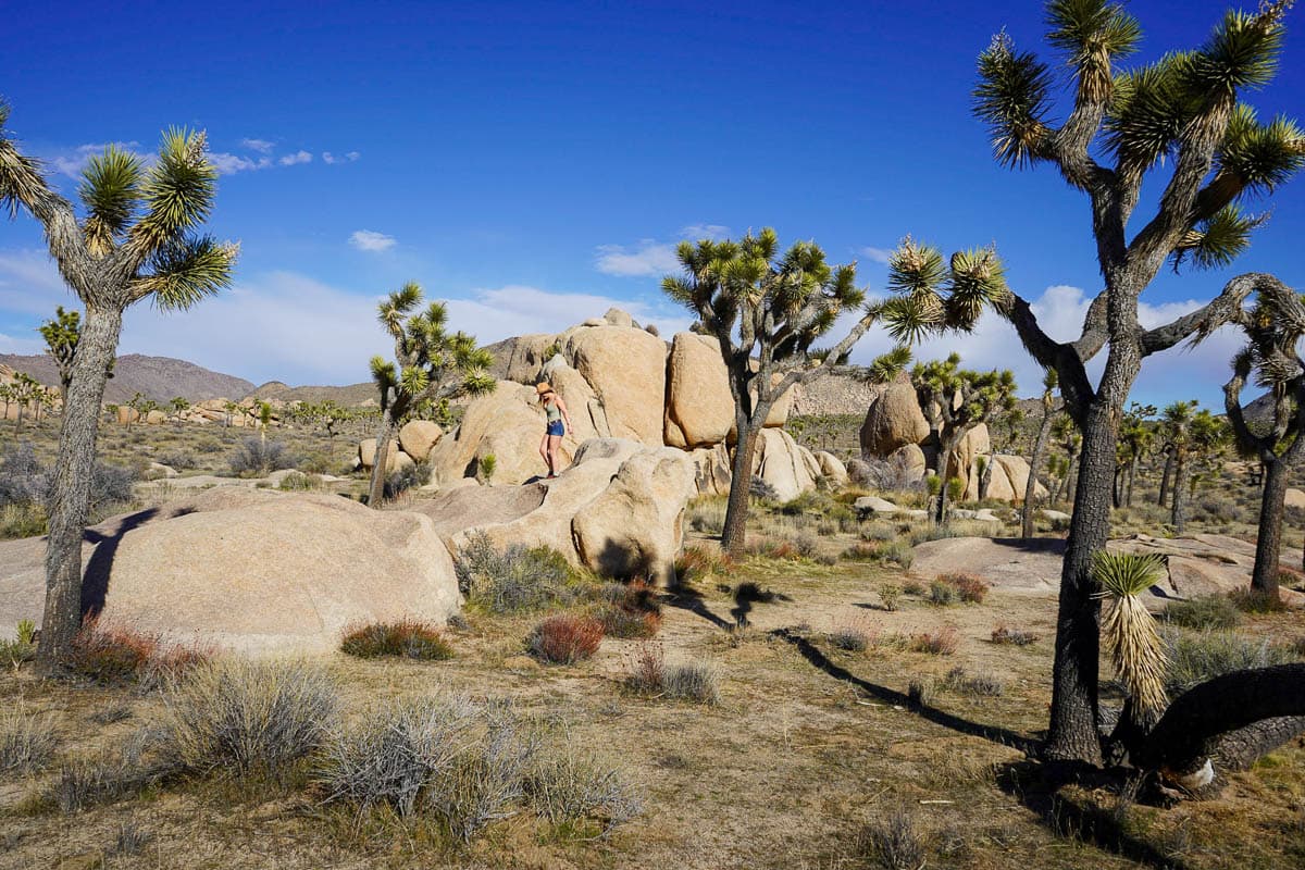 Woman walking on a monzogranite boulder along the Hidden Valley Trail in Joshua Tree National Park, California